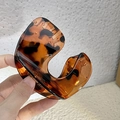 Matte amber tortoiseshell large hair claw clip in brown leopard print held by hand - Leopard Print Arch Claw Clip