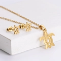 Minimalist gold stainless steel turtle jewelry set with necklace and earrings on white stone - Gold Hollow Sea Turtle Set