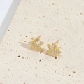 Dettaglio orecchini a foglia d'acero dorata con zirconi su un piedistallo in pietra - Foglia di Zircone Oro Grande