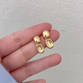 Close-up of hand holding a minimalist oval gold earring with polished metallic luster - Minimalist Geometric Oval