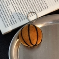 Handmade brown wool felt basketball keychain with silver metal ring on a tray - Basketball