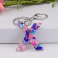 Resin letter X keychain featuring colorful stone fragments and silver lobster clasp - Letter X