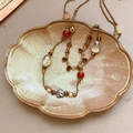 Détail d'un collier vintage perlé avec fleurs en céramique et cristaux ambrés sur plateau - Collier Or Rouge Café