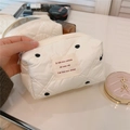 Detail der cremeweißen gesteppten Kosmetiktasche mit schwarzen Punkten und Webetikett - Schwarze Punkte