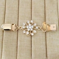 Détail macro de l'attache-pull fleur dorée avec cristaux brillants sur tissu beige - Style 9 (Flocon de neige en strass dorés)