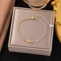 Macro view of two-tone stainless steel snake chain bracelet with elegant knot detail - Two-Tone Spliced Knot Bracelet