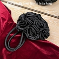 Close-up of black satin rose floral handbag on red velvet luxury background - Black