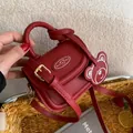 Mini sac à main en cuir PU rouge avec breloque ours tenu à la main en décor lifestyle - Rouge
