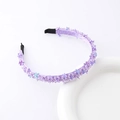 Detailed macro shot of a purple crystal flower headband with blue sequins on white ceramic - Purple
