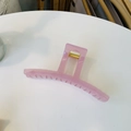 Pinza para el cabello minimalista de resina rosa con resorte dorado sobre fondo blanco - Rosa Gelatina