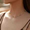 Close-up of gold-plated necklace featuring green evil eye beads and crystal charms on a model - 18K Gold