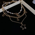 Detail of layered gold star necklace featuring white pearls on a black velvet background - Gold Necklace (3-Piece Set)