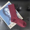 Single burgundy ribbed knit calf sock placed on an Acne Studios magazine and black leather - Short Angora Red
