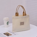 Mini cream canvas tote bag with brown handles and love bear patch in soft sunlight - Off White
