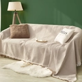 Beige waffle weave sofa cover with decorative tassels on a cozy living room couch - 130x180cm / Khaki