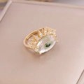 Makroaufnahme Goldring mit bösem Blick, grüner Pupille und Zirkonia auf Samt-Display - Einstellbar Offen / Grün