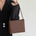 Detail of a brown leather tote bag with simple & natural text shown held by a model - Dark Brown