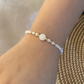 Beaded letter M bracelet with white round beads and gold accents worn on a woman's wrist - Letter M Style (M)