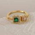 Close-up of gold-plated ring with emerald green stone on white lace fabric - Adjustable Open / Green Square Main Stone/Gold Band (13149)