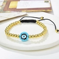 Macro shot of handcrafted evil eye charm with golden beads on black braided cord - Blue Center Eye Style (221025-B-G-7)