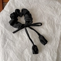 Detail of black satin scrunchie featuring elegant ribbon and tulip flower pendant - Black
