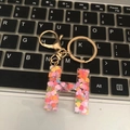 Close-up of letter H keychain with colorful heart glitter on a black keyboard - Letter H