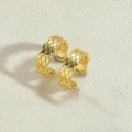 Dettaglio macro di orecchino a clip dorato con motivo a rombi su base in pietra - Placcato Oro 14K Ear Cuff Modello Trapuntato