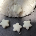 Close-up of cream flocked star pendants with metal rings for DIY jewelry making - Off-white