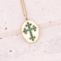 Detail of gold cross necklace with green gemstone inlay on textured stone background - Oval Green Crystal Cross (7#)