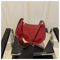 Close-up of a glossy red patent leather shoulder bag with a gold zipper on a chair - Red
