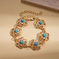 Dettaglio del bracciale a fiori con pietre verdi e cristalli su maglie dorate - Bracciale-Blu