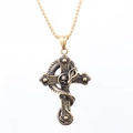 Detalle de colgante de cruz gótica de bronce con serpiente y calavera en cadena dorada - Estilo Dorado
