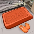 Absorbent orange soap-shaped bathroom mat with 3D soap text and soft fabric texture - Soap Orange