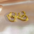 Polished 18k gold plated stainless steel heart earrings on pink silk background - Hollow Heart Hoop Style (EH263)