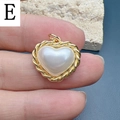 Dettaglio del ciondolo a cuore con perla finta bianca e bordo dorato intrecciato - Stile E-Ciondolo a Cuore con Perla e Bordo Intrecciato
