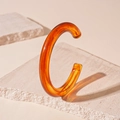 Dettaglio macro di un bracciale a C in resina ambrata su fondo di pietra naturale - Ambra