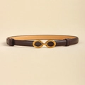 Detailed view of deep brown slim leather belt with golden horseshoe buckle on beige backdrop - Coffee