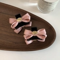 Detail of pink bow hair clips with gold charm and engraved text on a wooden tray - Pink