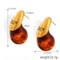 Macro detail of tear-shaped earrings showing golden copper texture and amber resin finish - F1506 Gold Color Resin Drop