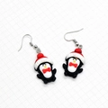 Detailed macro view of cute resin penguin Christmas earrings with metal hooks - Penguin with Hat