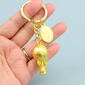 Gold metal soccer trophy keychain with blank oval tag held against a blue background - Football Trophy and Engraving Tag Style