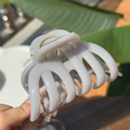 Pinza para el pelo grande color crema en forma de calabaza sostenida con luz natural - Gris Cemento