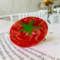 Detailed close-up of tomato-shaped hair claw clip with red rhinestones on a magazine - Rhinestone Tomato