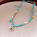 Dettaglio della collana boho con perline di turchese, pendente a sole dorato e perle - Oro-Blu