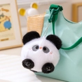 Llavero de peluche de panda con pelo blanco y negro colgado en un bolso de lona verde - Panda