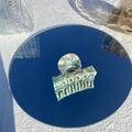 Artistic close-up of marble pattern acetate hair claw clip reflecting on a round mirror - Mint Ice