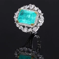 Macro shot of an emerald-cut green gemstone ring with marquise side stones and gold claws - Paraiba Blue