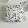 Close-up of quilted floral cosmetic bag with cotton fabric and metallic zipper detail - Black Floral with Label and Ribbon