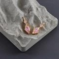 Detailed macro view of pear-shaped pink zircon earrings on a textured stone surface - Gold Base - Pink Zircon