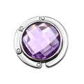 Macro view of a portable folding bag hook featuring a purple faceted crystal and silver frame - Light Purple